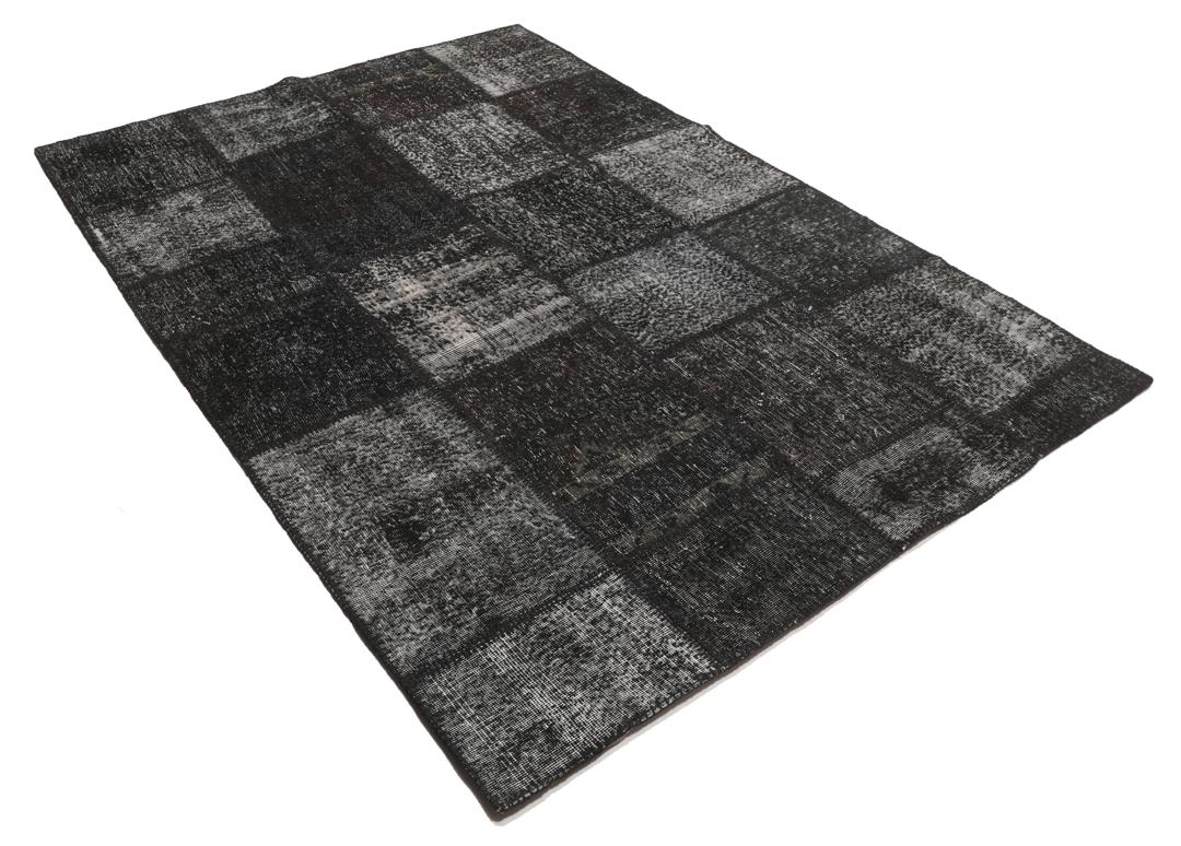 Een rechthoekig patchwork tapijt uit Turkije met een zwart-grijs ontwerp.