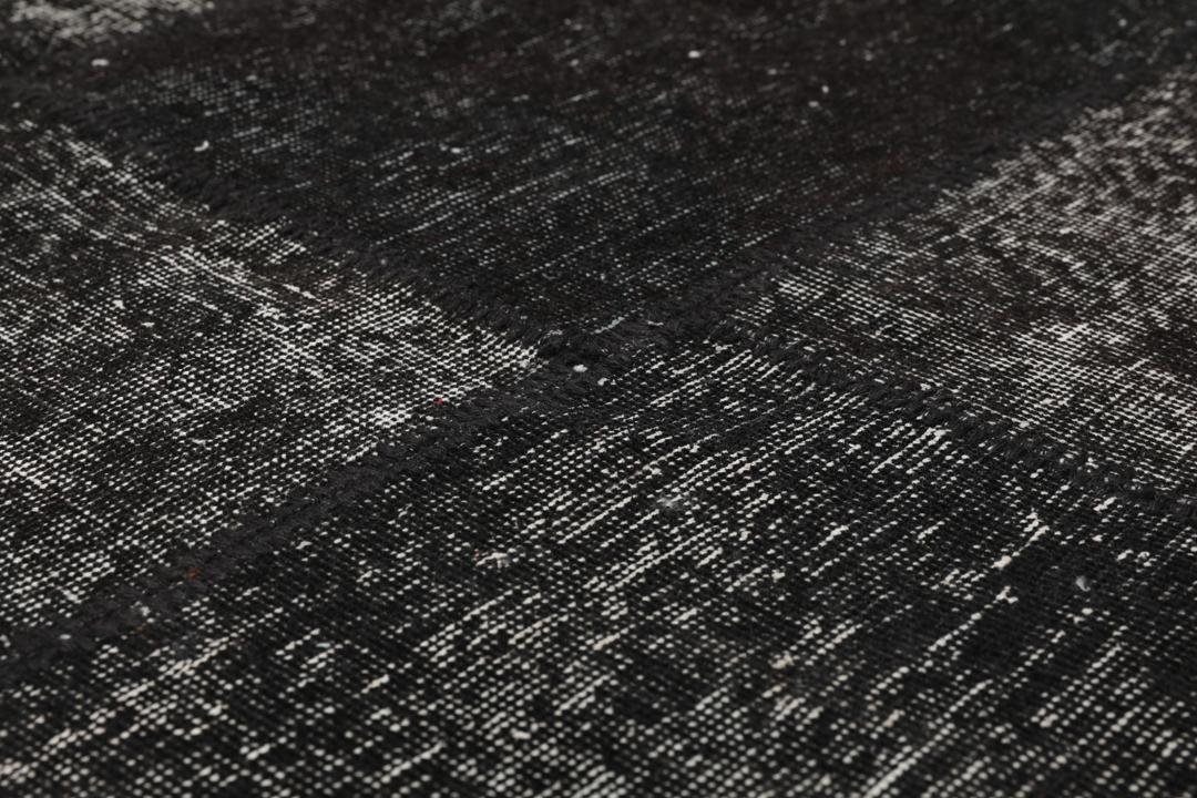 Een rechthoekig patchwork tapijt uit Turkije met een zwart-grijs ontwerp.