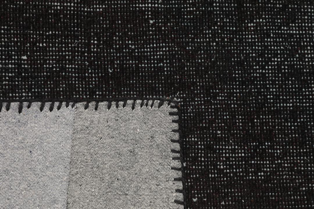 Een rechthoekig patchwork tapijt uit Turkije met een zwart-grijs ontwerp.