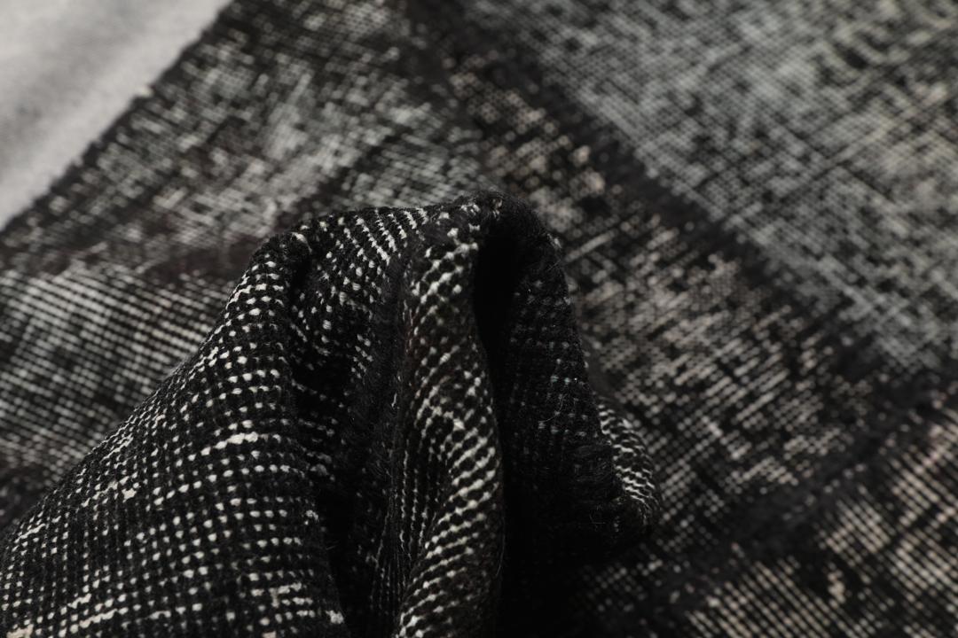 Een rechthoekig patchwork tapijt uit Turkije met een zwart-grijs ontwerp.