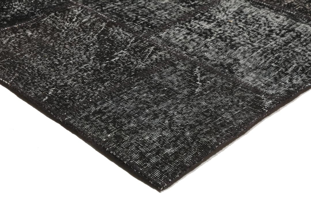 Een uniek handgemaakt patchwork tapijt uit Turkije in tinten zwart en antraciet.