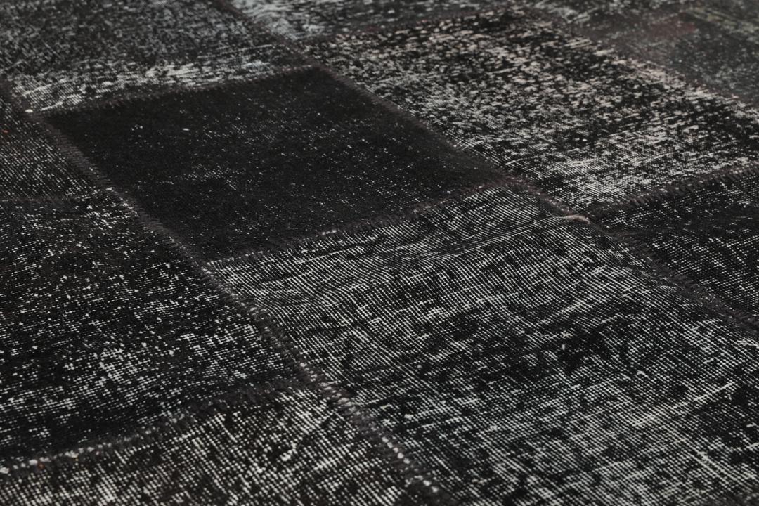 Een uniek handgemaakt patchwork tapijt uit Turkije in tinten zwart en antraciet.