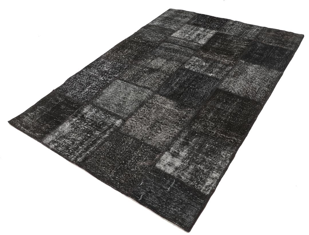 Een uniek, handgeknoopt zwart patchwork tapijt van Turkse oorsprong.