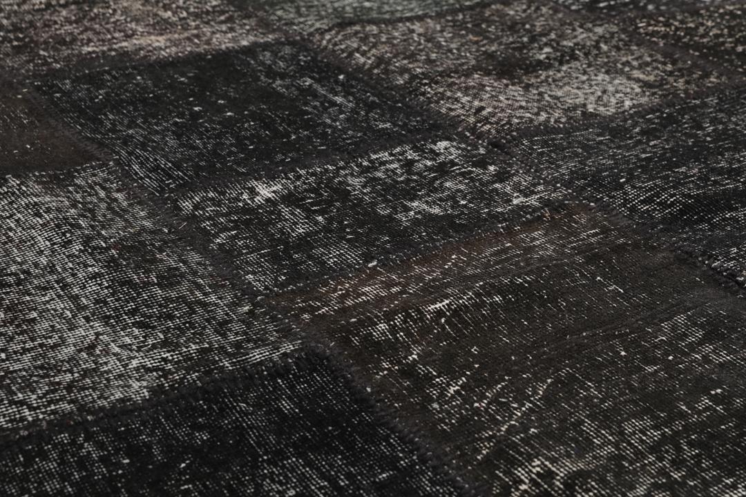 Een uniek, handgeknoopt zwart patchwork tapijt van Turkse oorsprong.