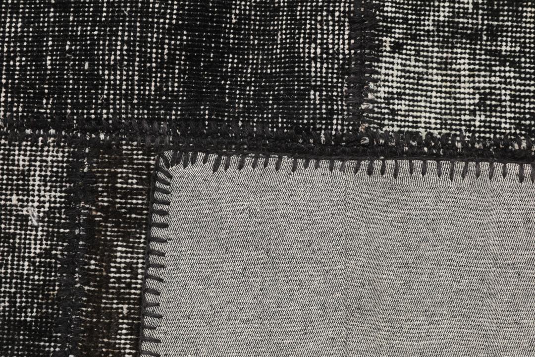 Een uniek, handgeknoopt zwart patchwork tapijt van Turkse oorsprong.