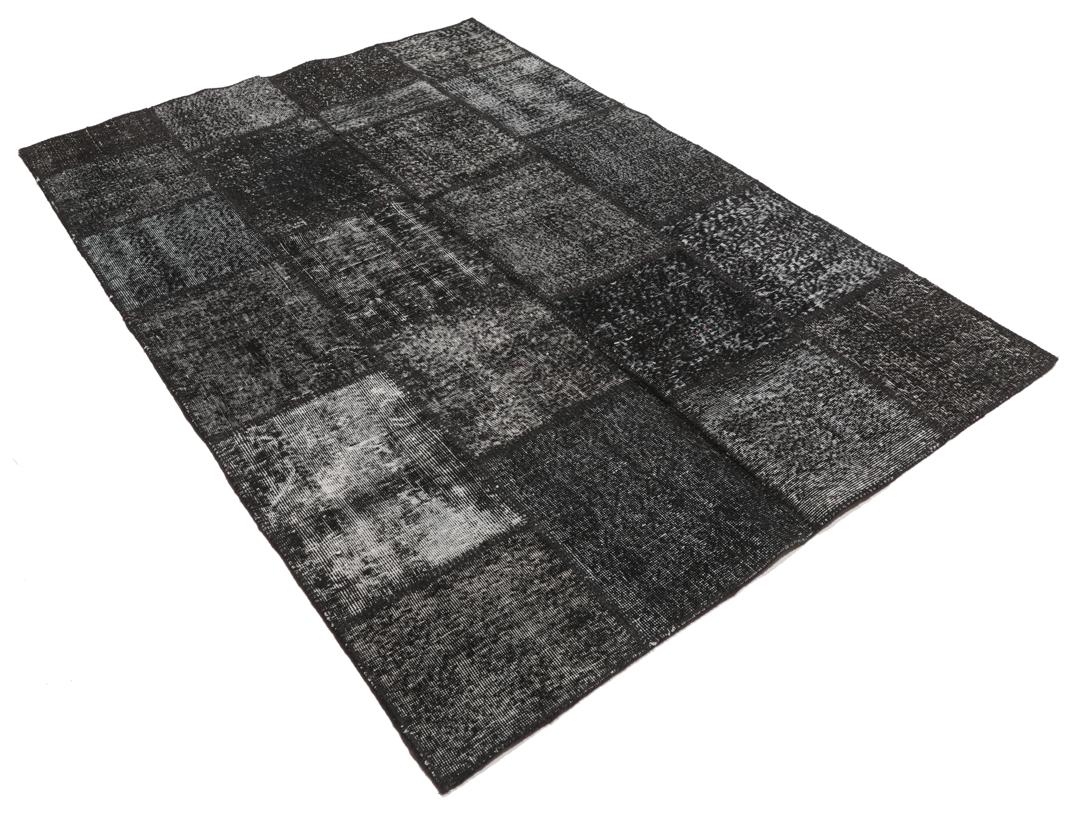 Een zwart patchwork tapijt met verschillende textuurpatronen uit Turkije