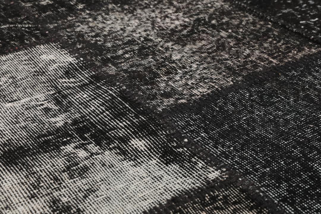 Een zwart patchwork tapijt met verschillende textuurpatronen uit Turkije