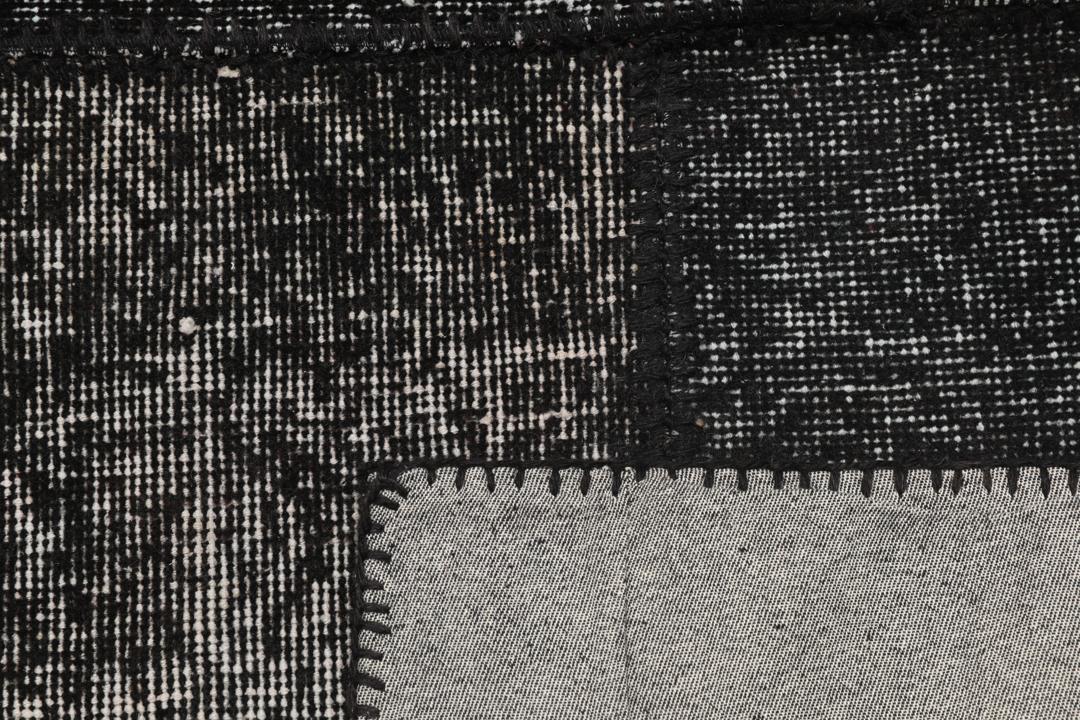 Een zwart patchwork tapijt met verschillende textuurpatronen uit Turkije