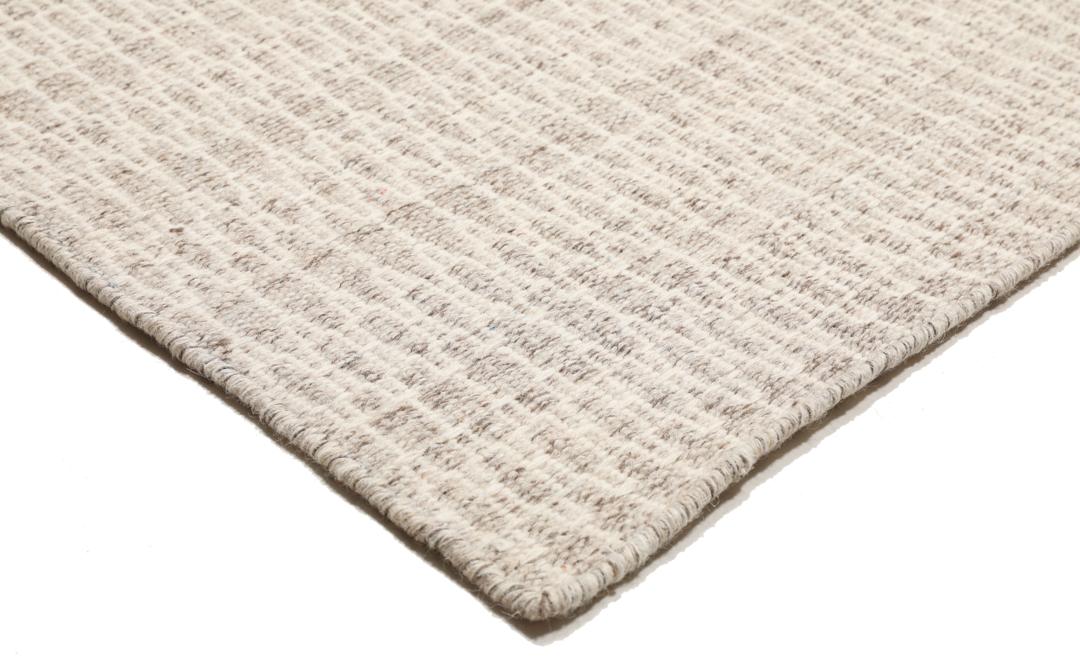 Beige tæppe med et struktureret vævet mønster