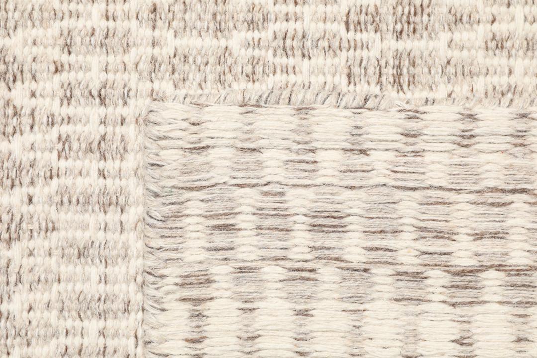 Beige tæppe med et struktureret vævet mønster