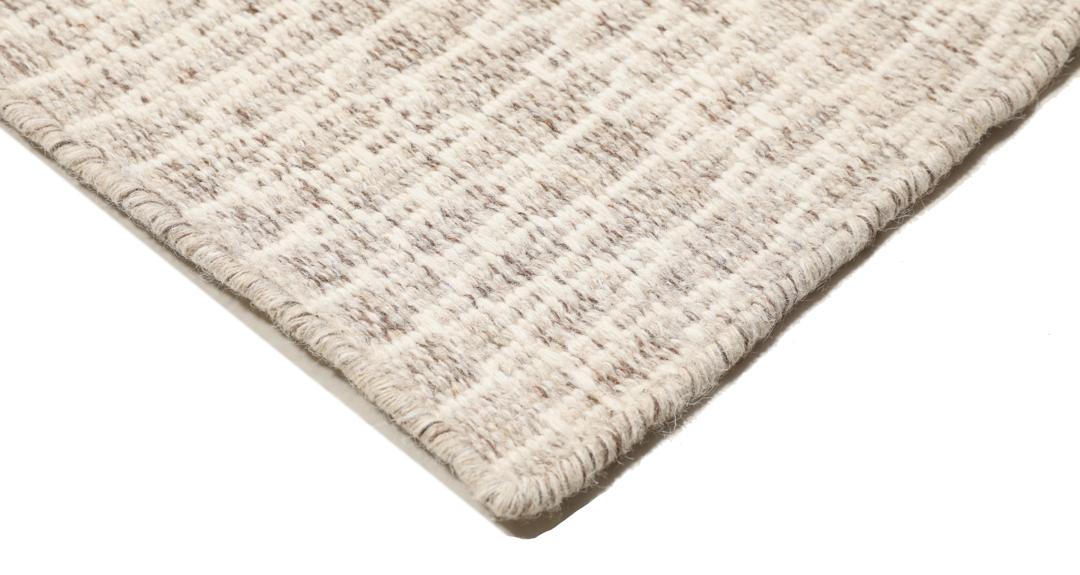 Beige tæppe med et struktureret vævet mønster