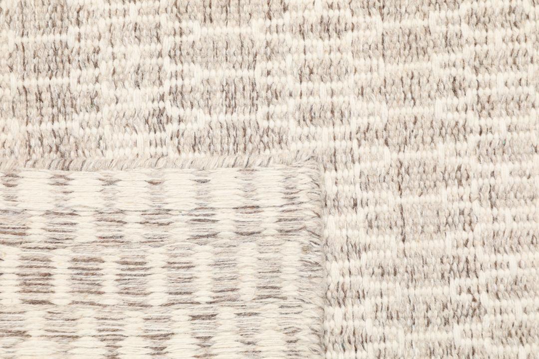 Beige tæppe med et struktureret vævet mønster