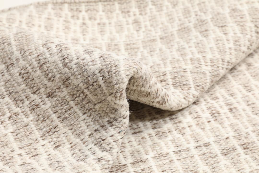 Beige tæppe med et struktureret vævet mønster