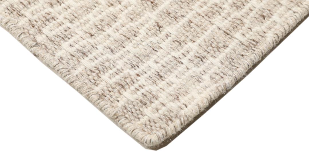 Beige tæppe med et struktureret vævet mønster