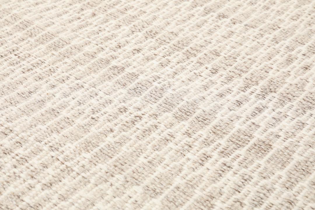 Beige tæppe med et struktureret vævet mønster