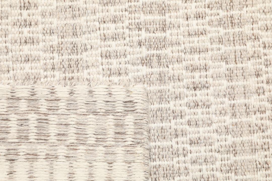 Beige tæppe med et struktureret vævet mønster