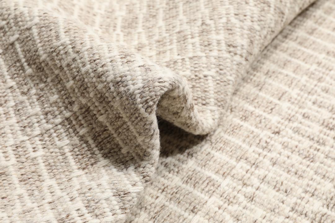 Beige tæppe med et struktureret vævet mønster