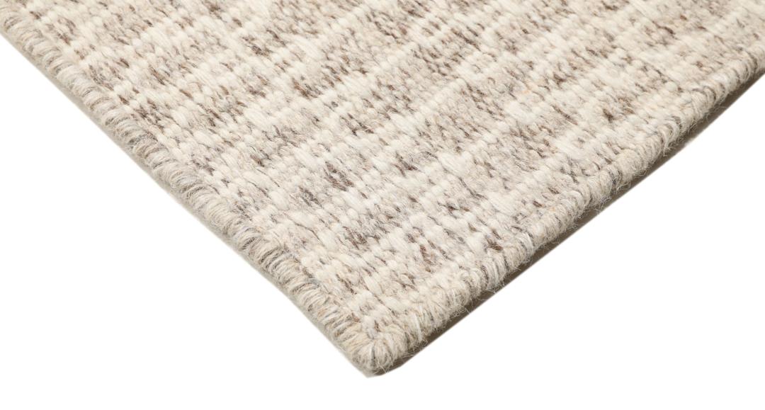 Beige tæppe med et struktureret vævet mønster
