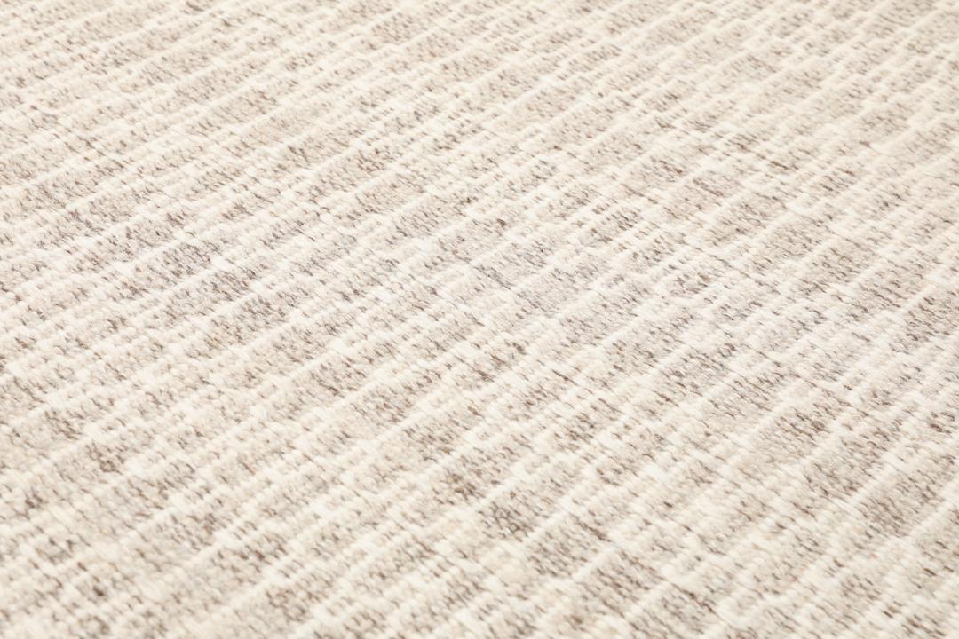 Beige tæppe med et struktureret vævet mønster