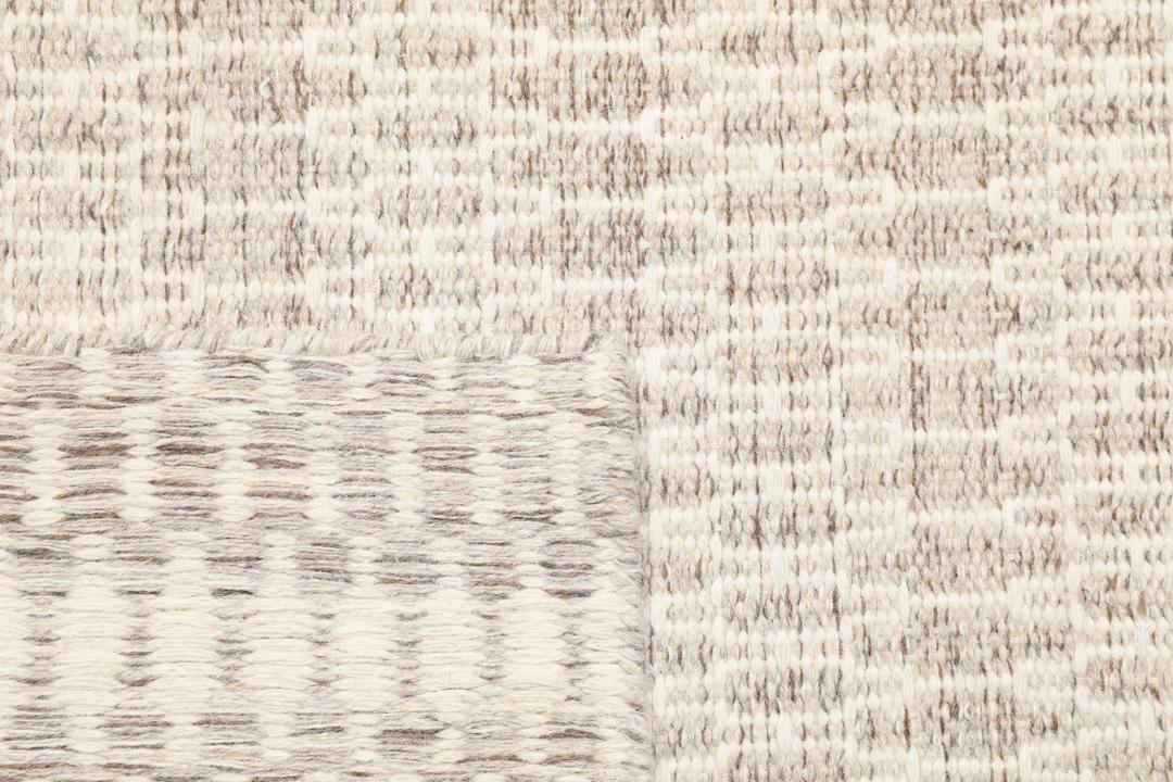 Beige tæppe med et struktureret vævet mønster