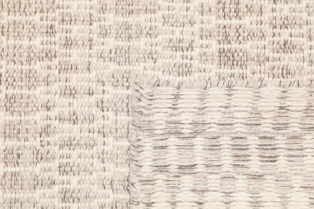 Beige tæppe med et struktureret vævet mønster