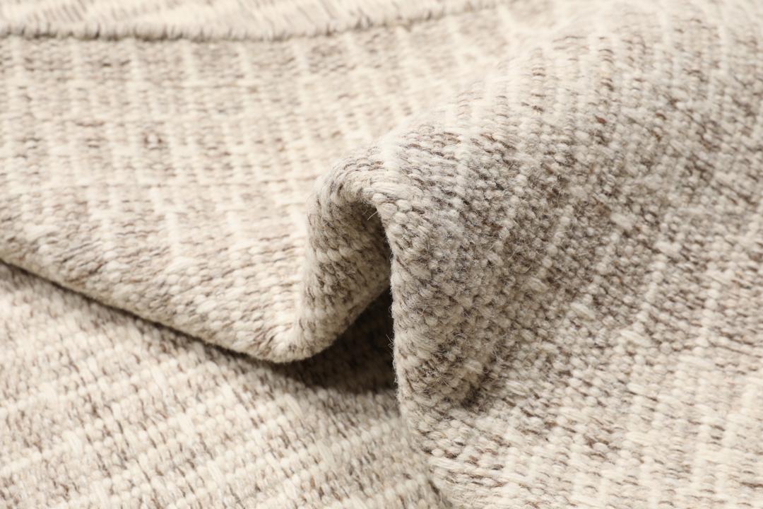 Beige tæppe med et struktureret vævet mønster