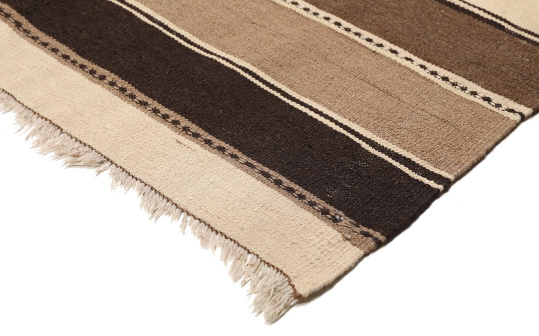 Et håndvævet Kelim-tæppe fra Mellemøsten med vandrette striber i brune, beige og mørke nuancer