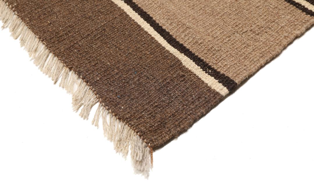 Et håndvævet brunt og beige stribet Kelim-tæppe fra Mellemøsten.