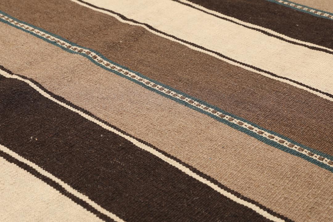 Håndvævet Kelim-tæppe fra Mellemøsten i nuancer af brun og beige med et stribet mønster.