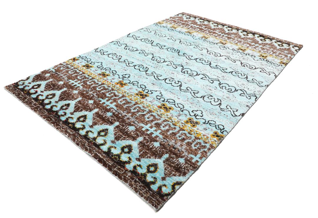 Tapis bleu clair noué main avec des motifs tribaux complexes
