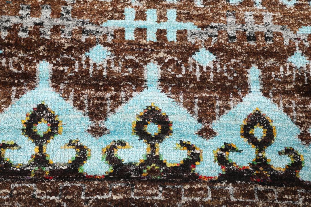 Tapis bleu clair noué main avec des motifs tribaux complexes