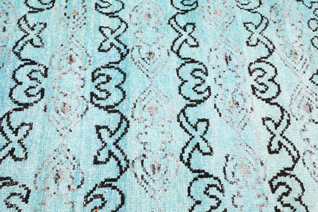 Tapis bleu clair noué main avec des motifs tribaux complexes