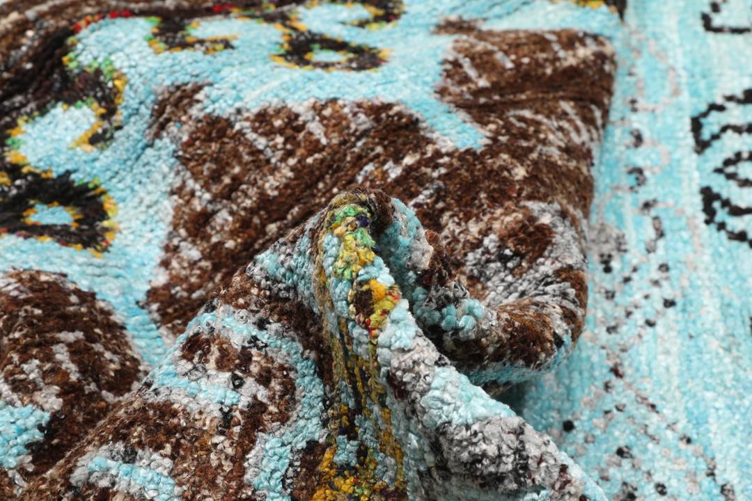 Tapis bleu clair noué main avec des motifs tribaux complexes
