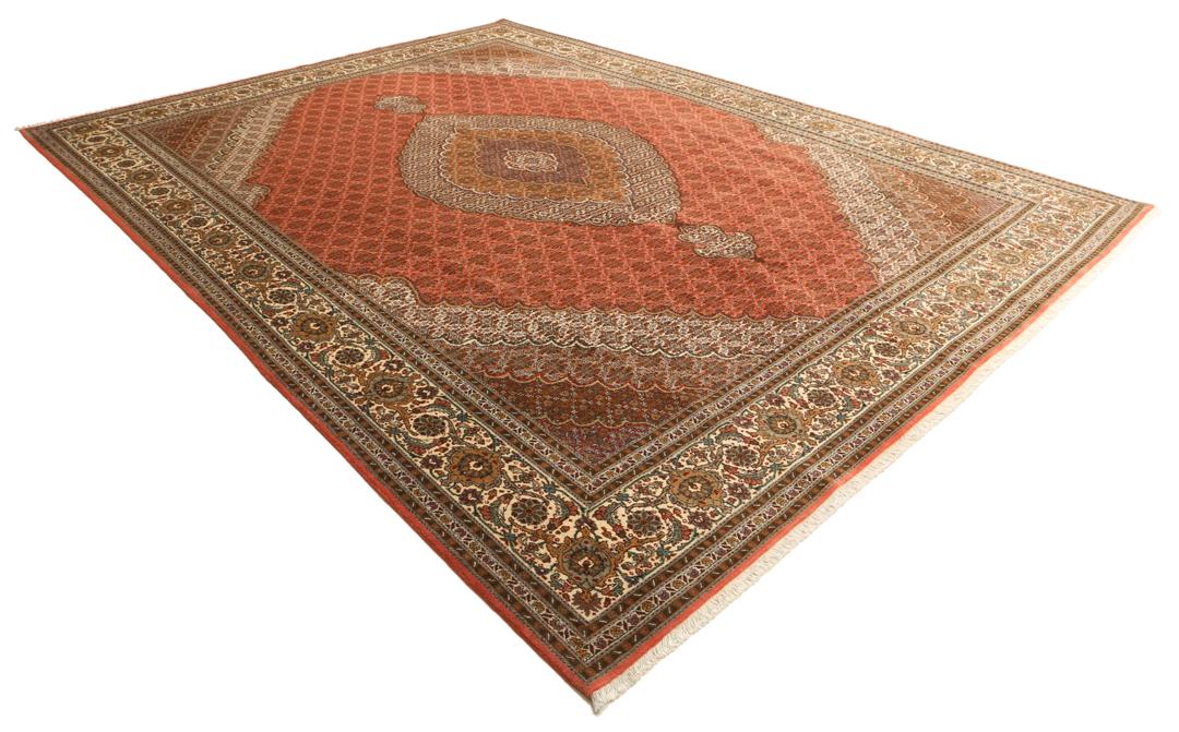 Et stort håndknyttet Tabriz-tæppe fra Mellemøsten i dybe røde og beige nuancer.