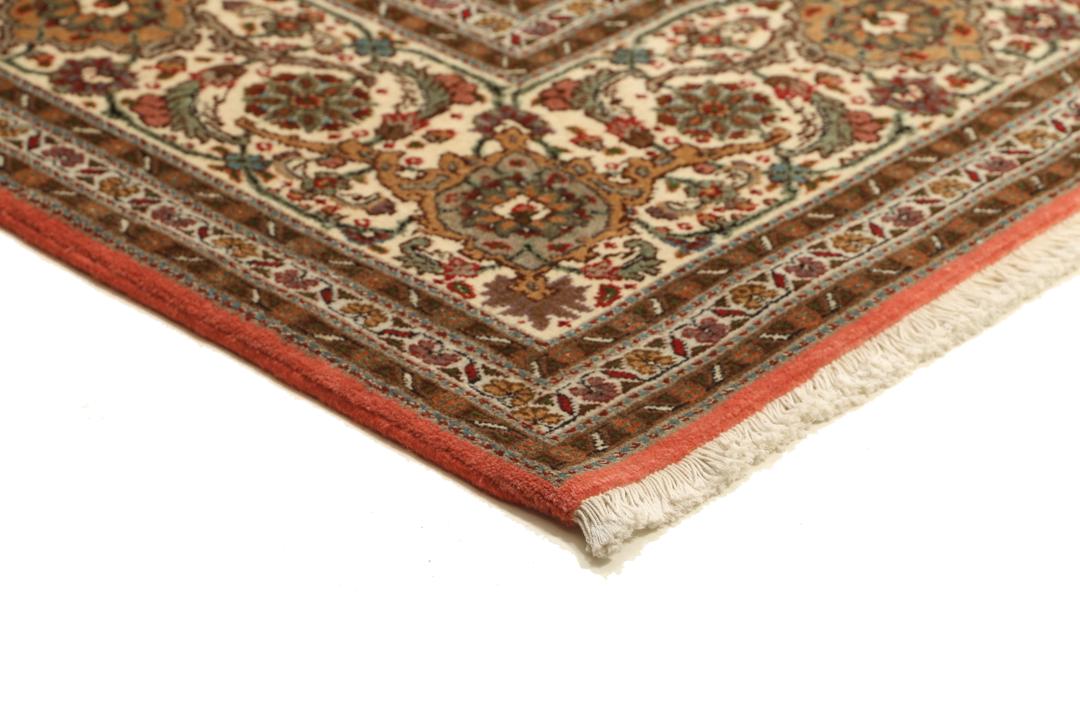 Et stort håndknyttet Tabriz-tæppe fra Mellemøsten i dybe røde og beige nuancer.