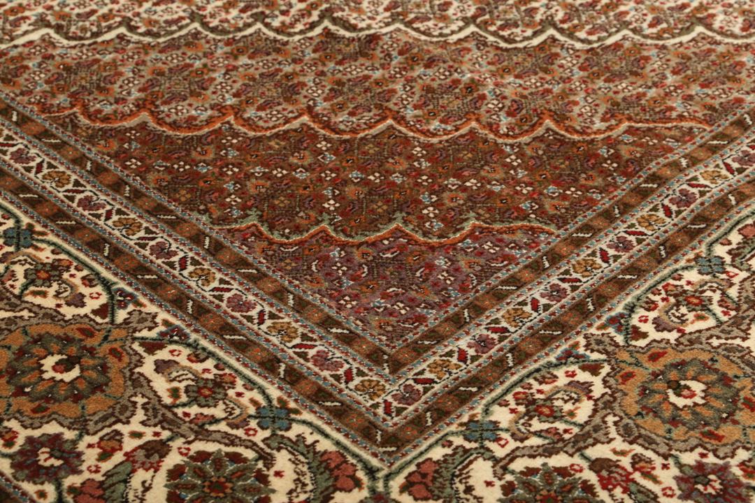 Et stort håndknyttet Tabriz-tæppe fra Mellemøsten i dybe røde og beige nuancer.