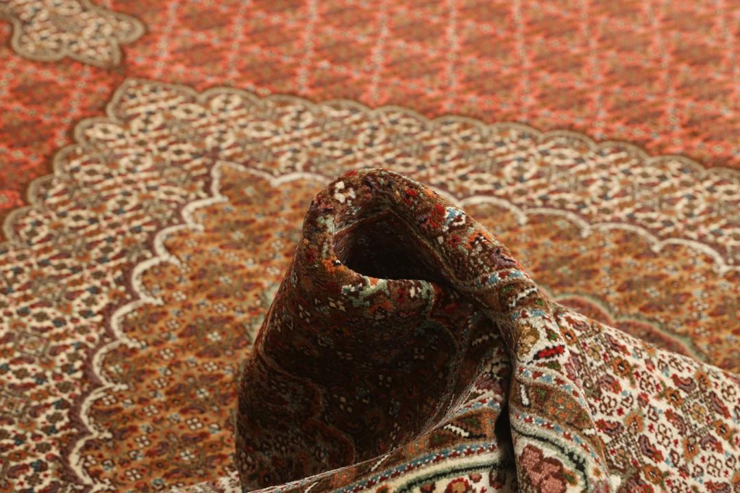 Et stort håndknyttet Tabriz-tæppe fra Mellemøsten i dybe røde og beige nuancer.