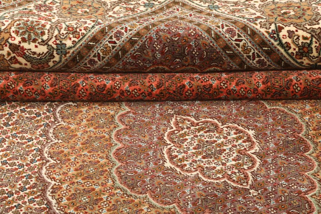Et stort håndknyttet Tabriz-tæppe fra Mellemøsten i dybe røde og beige nuancer.