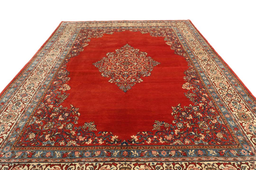 A hand-knotted Sarough rug from the Middle East featuring a red field and intricate floral medallion.