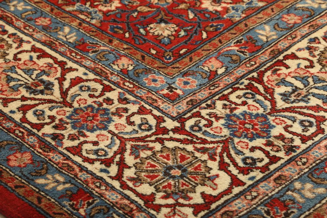 A hand-knotted Sarough rug from the Middle East featuring a red field and intricate floral medallion.