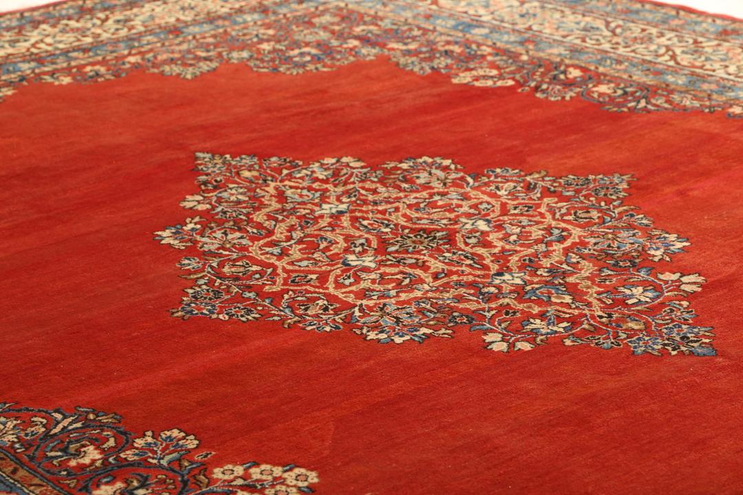 A hand-knotted Sarough rug from the Middle East featuring a red field and intricate floral medallion.