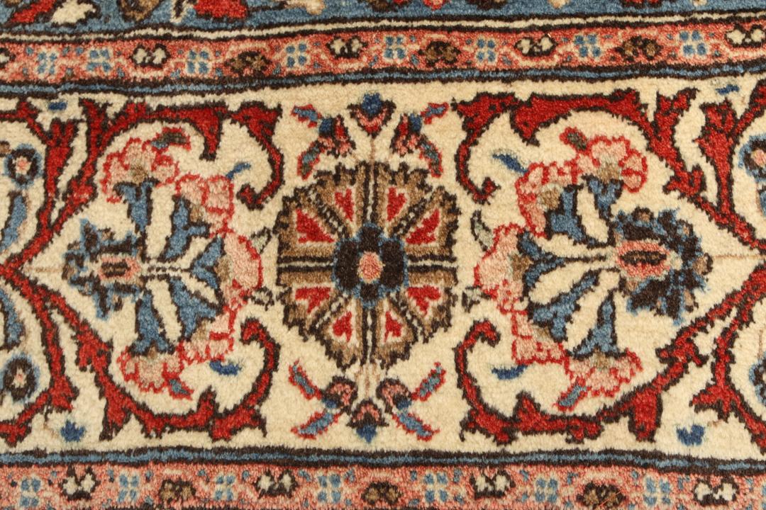 A hand-knotted Sarough rug from the Middle East featuring a red field and intricate floral medallion.