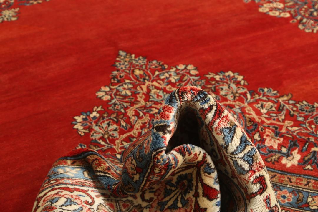 A hand-knotted Sarough rug from the Middle East featuring a red field and intricate floral medallion.
