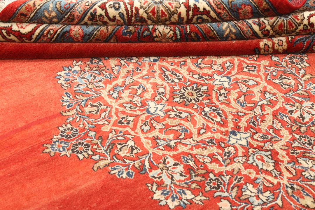 A hand-knotted Sarough rug from the Middle East featuring a red field and intricate floral medallion.