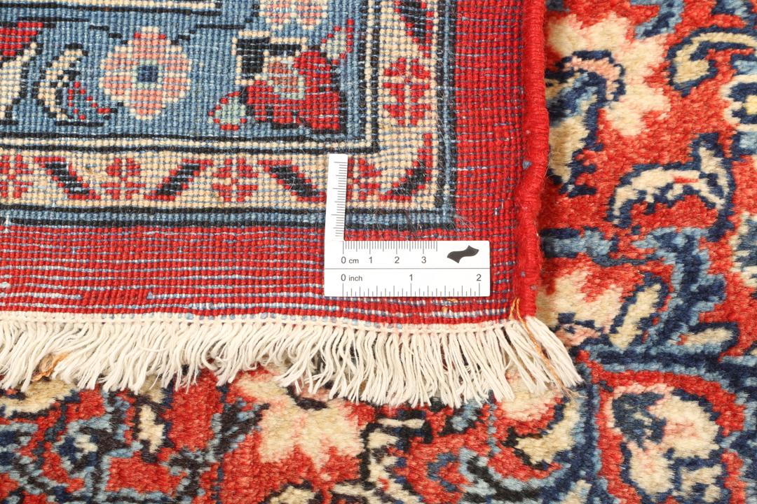 A hand-knotted Sarough rug from the Middle East featuring a red field and intricate floral medallion.