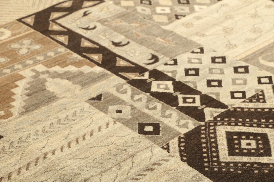 Et stort rektangulært håndknyttet moderne tæppe fra Indien med et brunt patchwork-design og forskellige geometriske mønstre.
