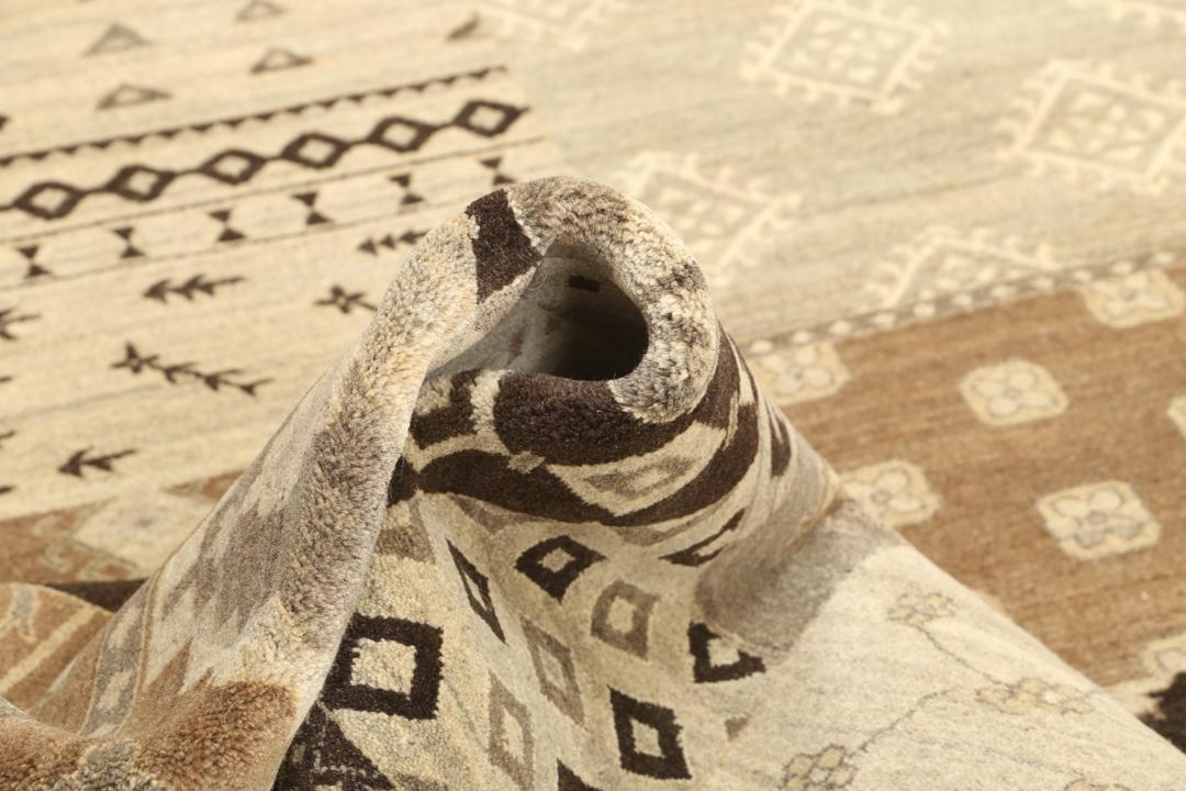 Et stort rektangulært håndknyttet moderne tæppe fra Indien med et brunt patchwork-design og forskellige geometriske mønstre.
