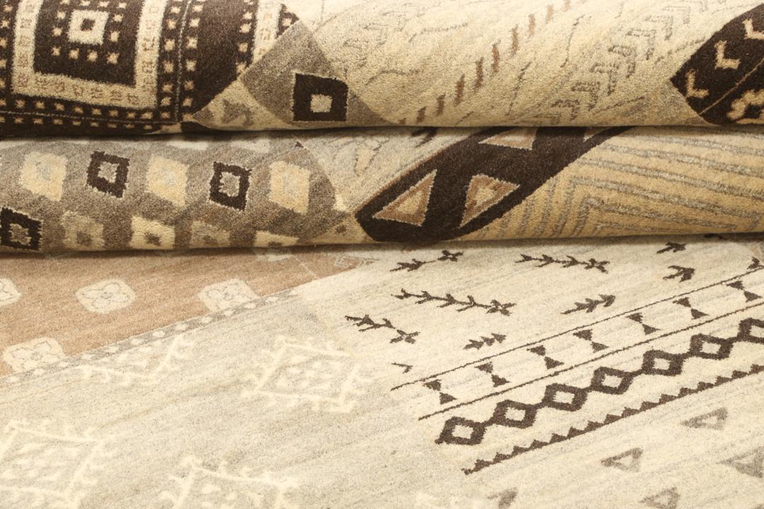 Et stort rektangulært håndknyttet moderne tæppe fra Indien med et brunt patchwork-design og forskellige geometriske mønstre.