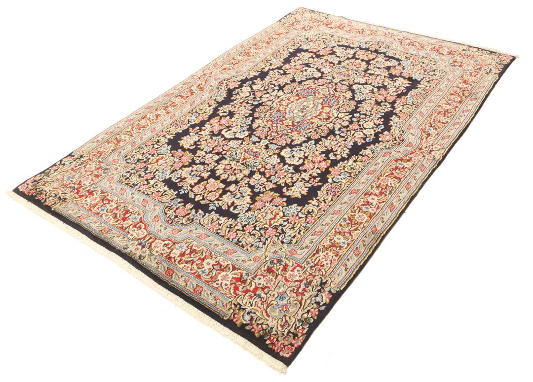 Een handgeknoopt Kerman-tapijt uit het Midden-Oosten met een diepblauw veld en bloemmotieven