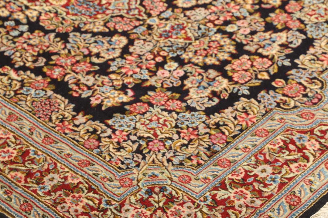 Een handgeknoopt Kerman-tapijt uit het Midden-Oosten met een diepblauw veld en bloemmotieven